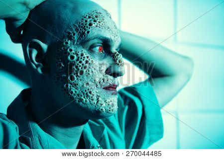 A close up portrait of a sick man in the blue light. Desparation, hopelessness.