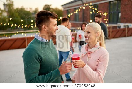 leisure, celebration and people concept - happy friends with non alcoholic drinks at rooftop party in evening