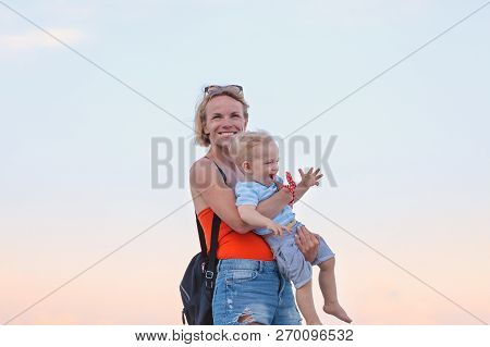 Woman Playing With Her Baby Outside Against The Sea. The Concept Of A Happy Full-fledged Family Life