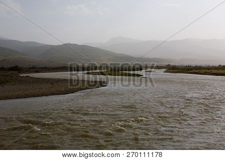 Rushing Stream Of The River And The Mountains In The Haze. Landscape.