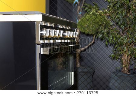 Black Gas Stove In The Kitchen Interior Against The Background Of Home Bonsai Tree