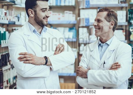 Two Pharmacists Looking At Each Other. Pharmacists Is A Caucasian Adult Man And Young Guy. Men Weari