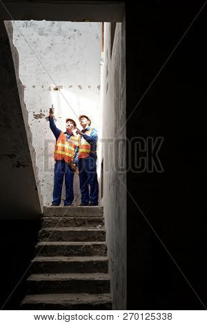 Vietnamese Workers Stainding On Stairs Of Building Under Construction And Discussing Work