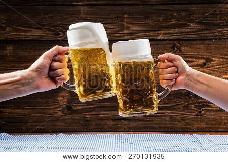 Hands Holding Mugs Of Bavarian Beer Oktoberfest.