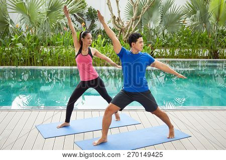 Sporty Young Asian Couple Exersicing Together On Yoga Mat