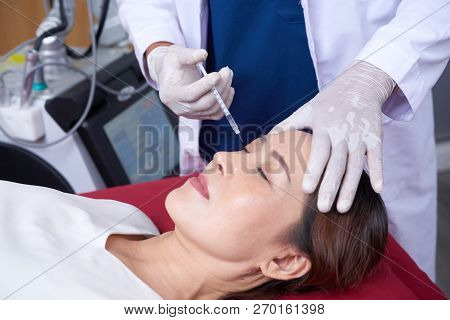 Mature Asian Woman Getting Botox Injection At Beauty Salon