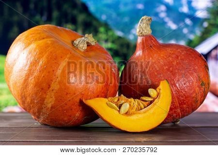 Group Of Two Whole One Slice Of Fresh Red Kuri Pumpkin Hokkaido Variety With Country Nature In Backg