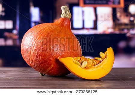 Group Of One Whole One Slice Of Fresh Red Kuri Pumpkin Hokkaido Variety With Restaurant In Backgroun