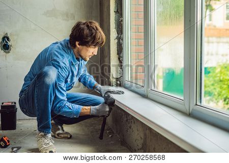 Man In A Blue Shirt Does Window Installation