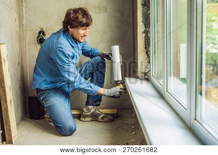 Man In A Blue Shirt Does Window Installation. Using A Mounting Foam