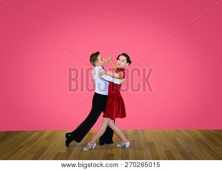 The Young Boy And Girl Posing At Dance Studio On Gray. The Ballroom Dancing Concept