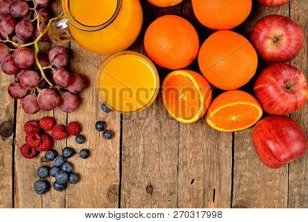 View From Above Of Jug With Orange Juice, Fresh Oranges, Apples, Grapes, Raspberries And Blueberries
