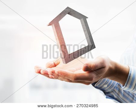 Cropped Image Of Businessman In Suit Keeping Stone House Symbol In Hands. Mixed Media