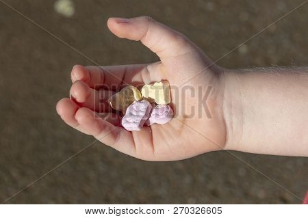 A Close Up View Of A Small Child Holding Four Animal Shaped Vitamins In The Plam Of His Hand