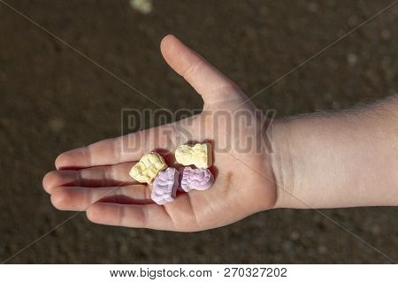 A Close Up View Of A Small Child Holding Four Animal Shaped Vitamins In The Plam Of His Hand