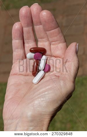 A Close Up View Of A Womens Plam Of Her Hand Holding Seven Pills