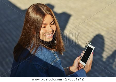 The Student Sits On A Bench And Listens To Music On The Phone With Headphones, Eyes Closed, Enjoying