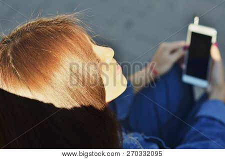 Portrait Of A Young Attractive Girl Dressed In Denim Clothes Who Enjoys Listening To Music Outside I