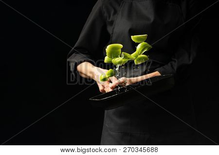 The Chef Cooks Green Tomatoes On The Pan. Black Background For Copying Text. Restaurant Business And