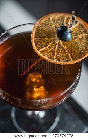 The Boulevardier Cocktail With Orange Chips On Top. On A Bar Desk