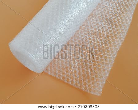 Transparent Bubble Wrap Roll For Packaging Fragile Items On Yellow Background Top View, Close Up