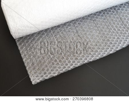 Transparent Bubble Wrap Roll For Packaging Fragile Items On Black Background Top View, Close Up