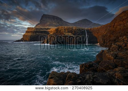 Mulafossur Waterfall On Vagar Island In Colorful Sunset, Faroe Islands