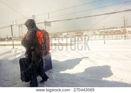 Tourist Man Hastily Walking And Holding Luggage To Keep Up The Train Amid The White Snow On Floor An
