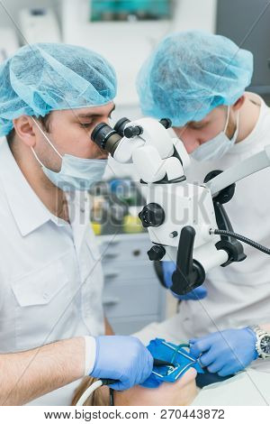 Doctor Used Microscope. Dentist Is Treating Patient In Modern Dental Office. Operation Is Carried Ou