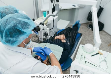 Doctor Used Microscope. Dentist Is Treating Patient In Modern Dental Office. Operation Is Carried Ou