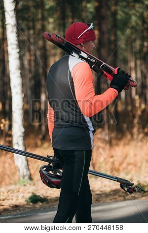 Training An Athlete On The Roller Skaters. Biathlon Ride On The Roller Skis With Ski Poles, In The H