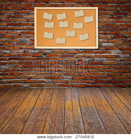 Bacheca in sughero con vecchia carta nota sul muro di mattoni.