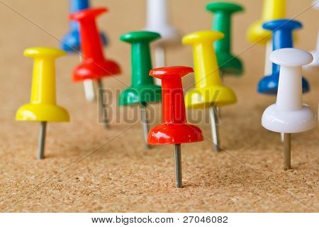 Gruppo di colorati push pin sulla bacheca di sughero.