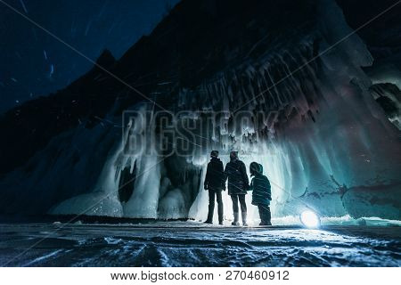 Surreal Landscape With People Exploring Mysterious Ice Grotto Cave. Outdoor Adventure. Family Explor