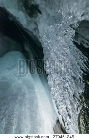 Winter Baikal. Olkhon Island. Ice Grotto. Thick Blue Ice And Icicles On The Coastal Rocks Of Olkhon 