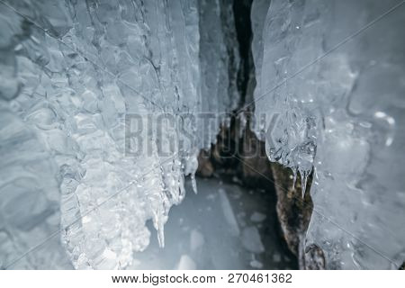 Winter Baikal. Olkhon Island. Ice Grotto. Thick Blue Ice And Icicles On The Coastal Rocks Of Olkhon 