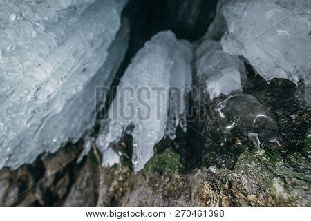 Winter Baikal. Olkhon Island. Ice Grotto. Thick Blue Ice And Icicles On The Coastal Rocks Of Olkhon 