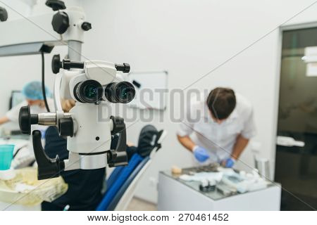 Doctor Used Microscope. Dentist Is Treating Patient In Modern Dental Office. Operation Is Carried Ou