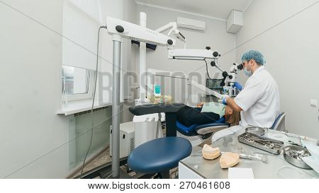 Doctor Used Microscope. Dentist Is Treating Patient In Modern Dental Office. Operation Is Carried Ou