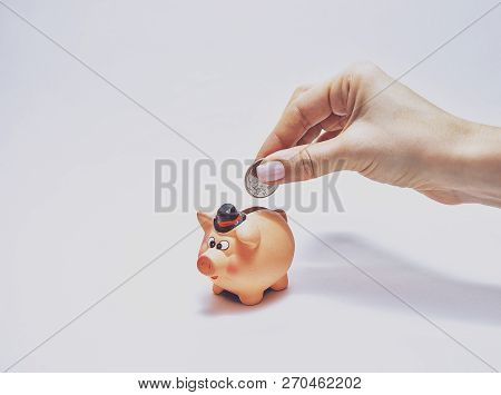 Woman Putting Coin Into Piggy Bank On White Background