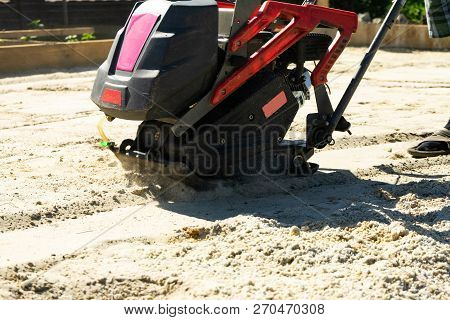 Builder With Vibratory Plates Seals The Base Sand For Pouring Concrete.