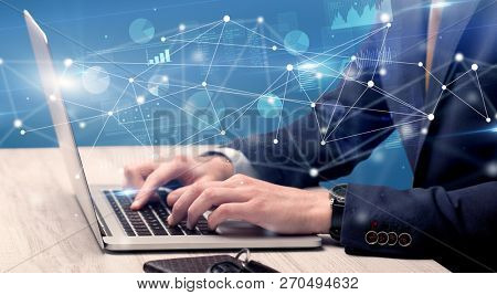 Businessman typing on laptop with linked reports charts grapghs around