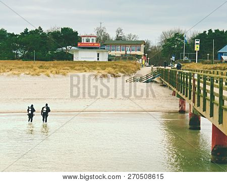 Prerow Germany - January 25 2018: Couple Of Sea Divers Walk From Sea To Beach. End Of Diving Lesson.