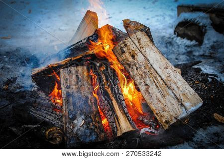 Burning Logs In A Snowy Winter With Smoke