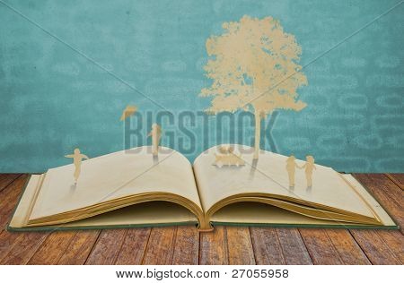Papel cortado del juego de los niños en el viejo libro