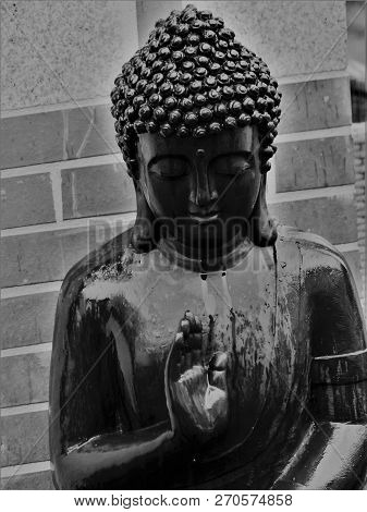 Bust Of Outdoor Black Buddha In Meditation In The Rain In Winter Of Day