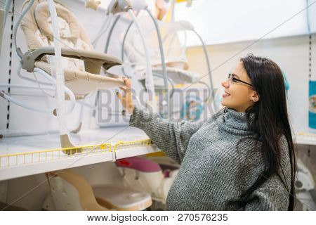 Pregnant woman choosing baby chair in store