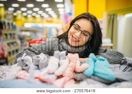 Future mother in glasses buys baby clothes