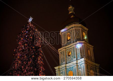 Christmas Tree With Lights Outdoors At Night In Kiev. Sophia Cathedral On Background. New Year Celeb