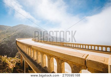Panoramic View Of Historic Bixby Creek Bridge Along World Famous Highway 1 On A Sunny Day With Fog I